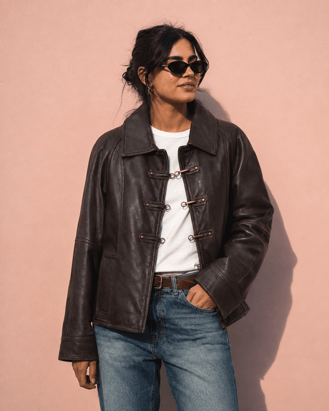 Woman in sunglasses wearing an oversized brown clasp jacket and jeans